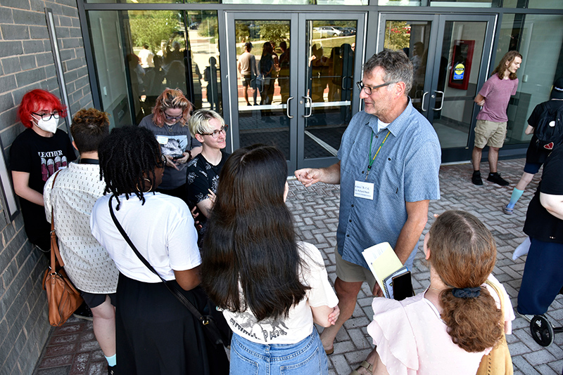 Seven students meet with faculty member outside of Shineman Hall