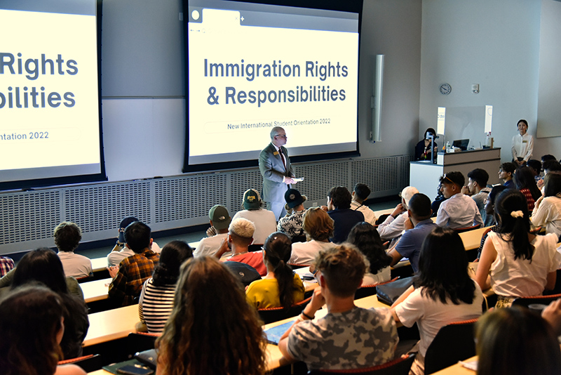 Joshua McKeown at International Student orientation in front of pull down screens that read "Immigration Rights and Responsibilities."