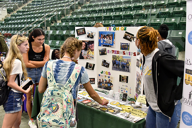 Students gather around the It's On Oz table to gather resources about Title IX and other campus resources