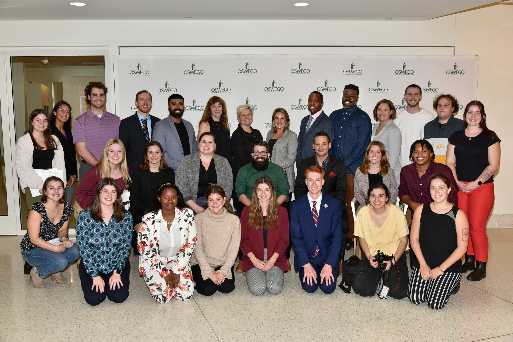 Mary Toale (standing seventh from left), SUNY Oswego Officer in Charge; and 2022 Media Summit faculty organizer David Crider (standing 4th from left), a communication studies faculty member, gather with  alumni panelists, career connectors, student hosts and organizers, and faculty members for a group photo before heading into Waterman Theatre for the Oct. 26 panel discussion.