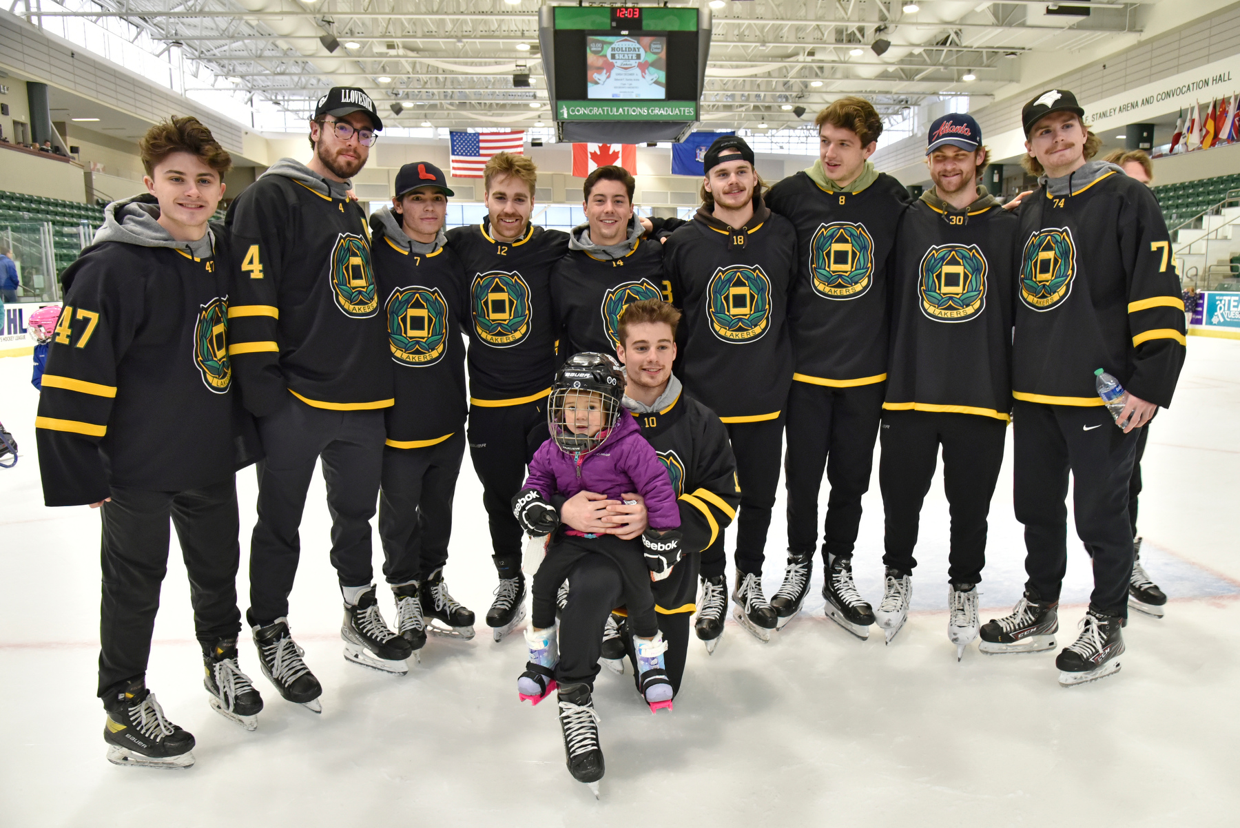 Laker Daniel Colabufo (#10), center, takes a moment to gather for a photo with his niece Mia Colabufo, 3, and other members of the men's hockey team during the popular annual Holiday Skate with the Lakers held Dec. 4.