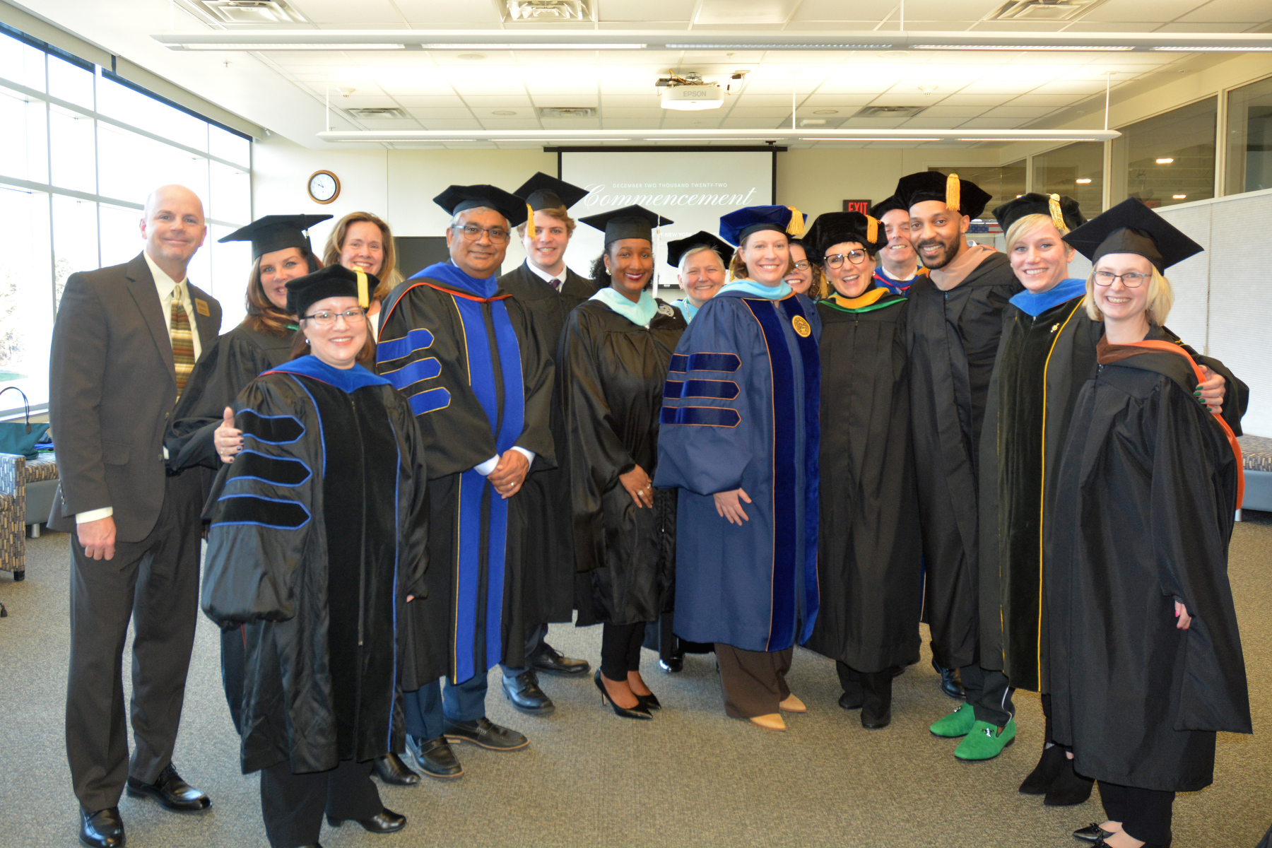 Cameron E. Jones, pictured third from right, gathers with college faculty and administrators prior to the December Commencement ceremony held Dec. 10 in Marano Campus Center. A 2009 SUNY Oswego broadcasting and mass communication graduate and manager of development for integrated content strategy for ABC News Studios, Jones served as the Commencement speaker.