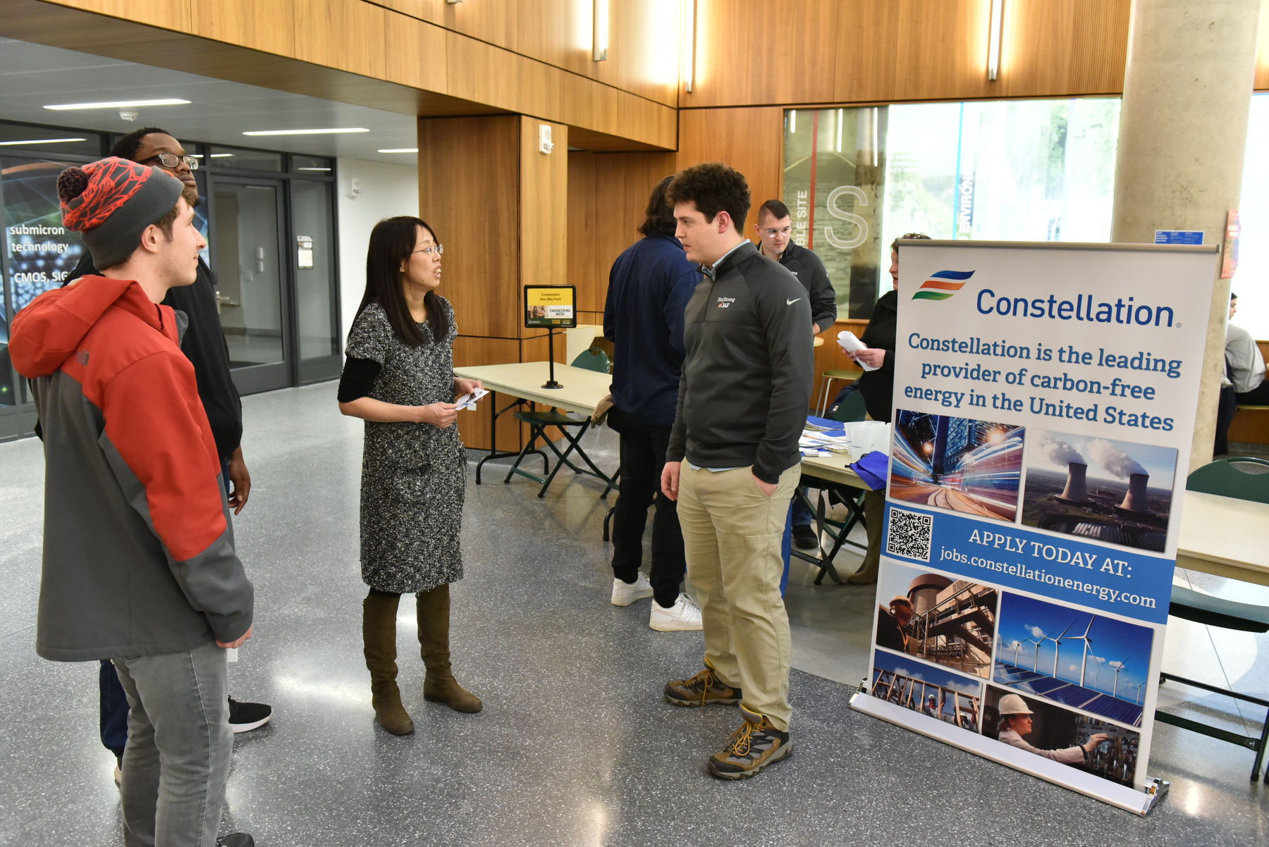 Avery Croucher (right), a 2022 electrical and computer engineering (ECE) graduate now with Constellation Energy, talks with Hui Zhang (center), an assistant professor in ECE, and students during the Engineering Industry Showcase