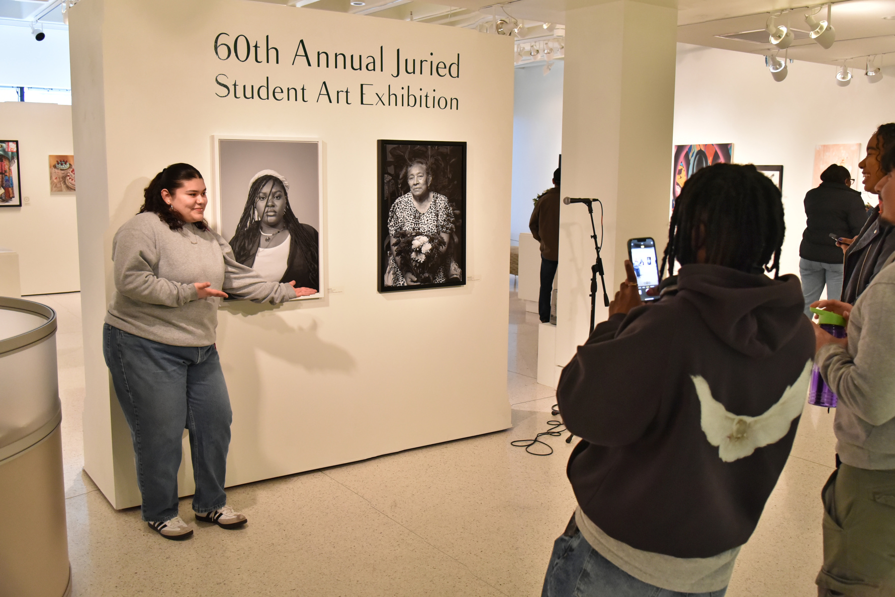 The 60th annual Juried Student Art Exhibition, open to all students to showcase their artistic talents, began with a reception March 24 in Tyler Art Gallery. Angelica Zelaya (pictured), a sophomore cinema and screen studies major, poses for a photo by friends with her large format archival pigment prints on display.