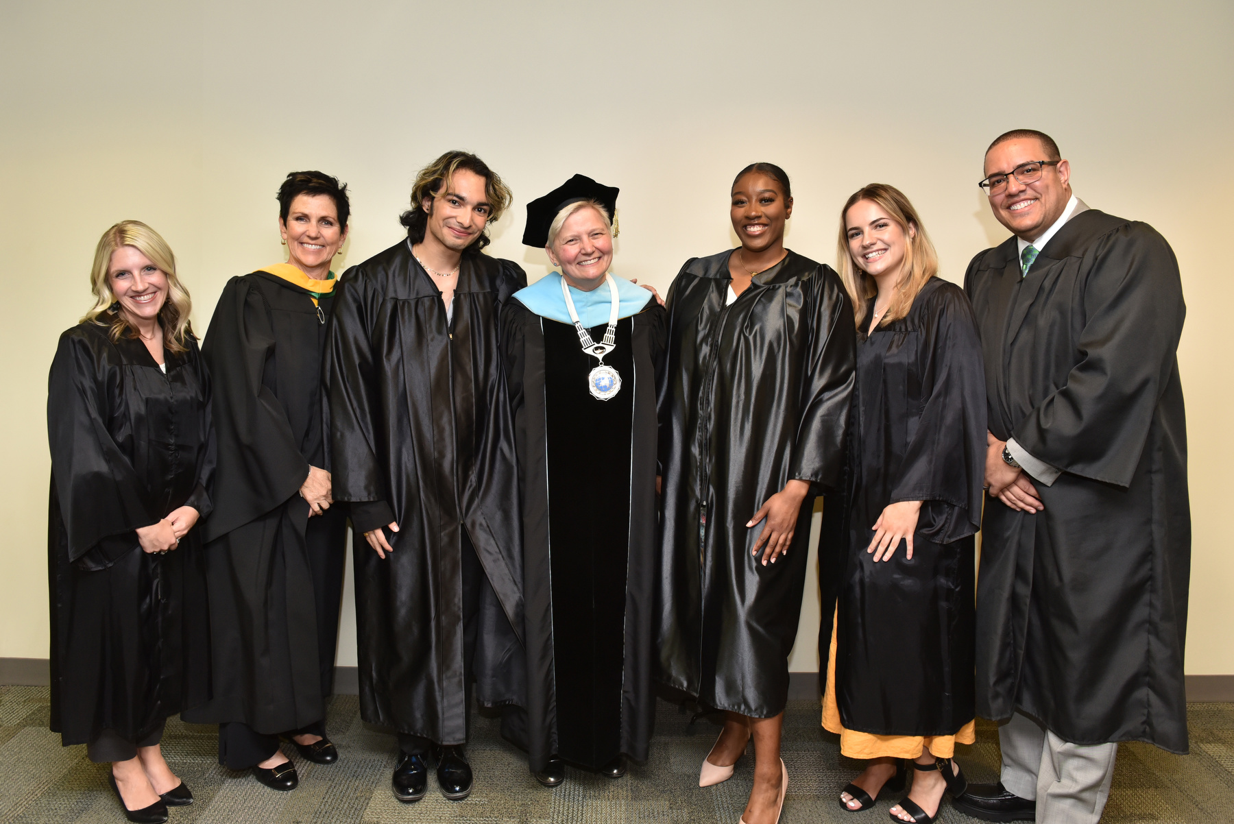 The Torchlight Ceremony platform party gathered for a photo, from left: Laura Pavlus Kelly '09, executive director of the Oswego Alumni Association, Inc.; Mary Gibbons Canale '81, vice president of development and alumni engagement; Kaushal Joshi '23, student speaker; Officer in Charge Mary C. Toale; Danielle Boxill '23, torchbearer; Amy Krohl '23, student emcee; and Gabriel Almanzar ’05, creative director for CBS News and Torchlight Speaker.