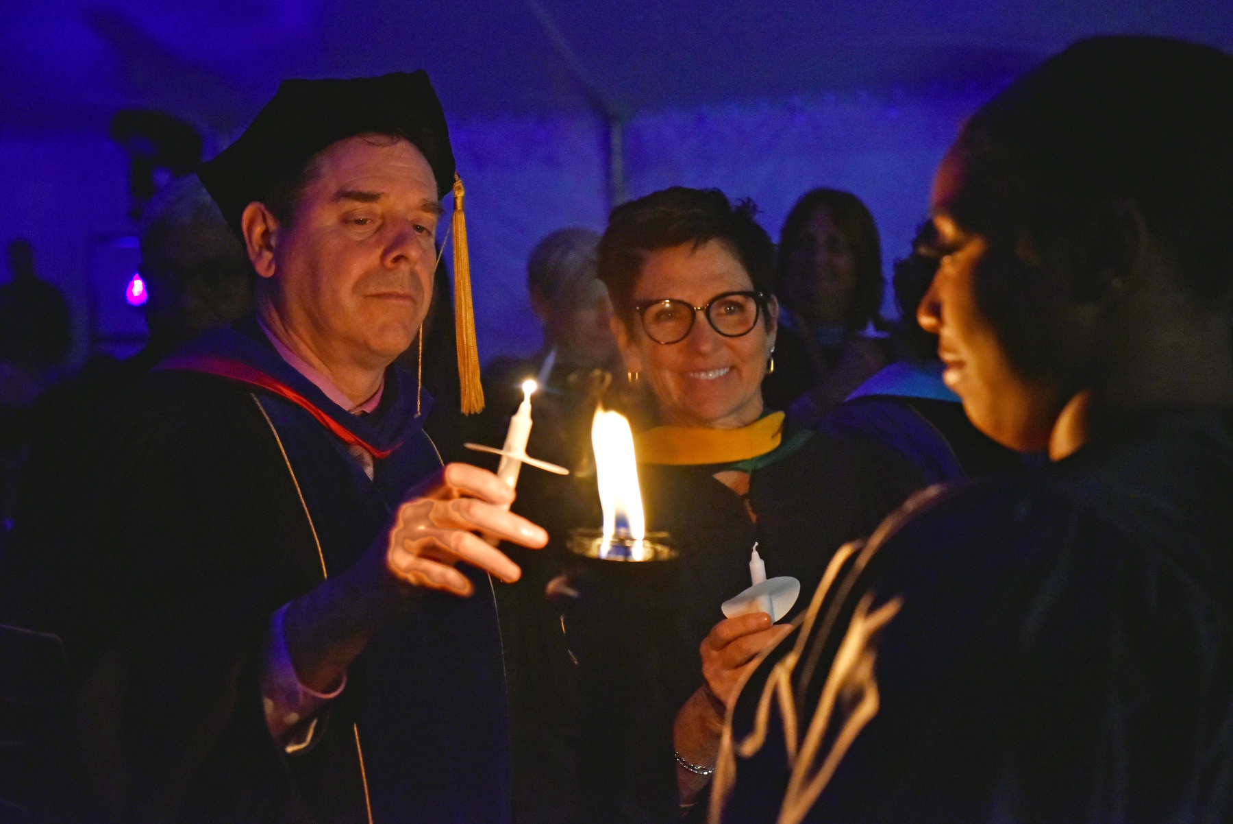 Torchbearer Danielle Boxill '23 lights the candles held by Provost Scott Furlong and Vice President of University Advancement Mary Gibbons Canale '81.