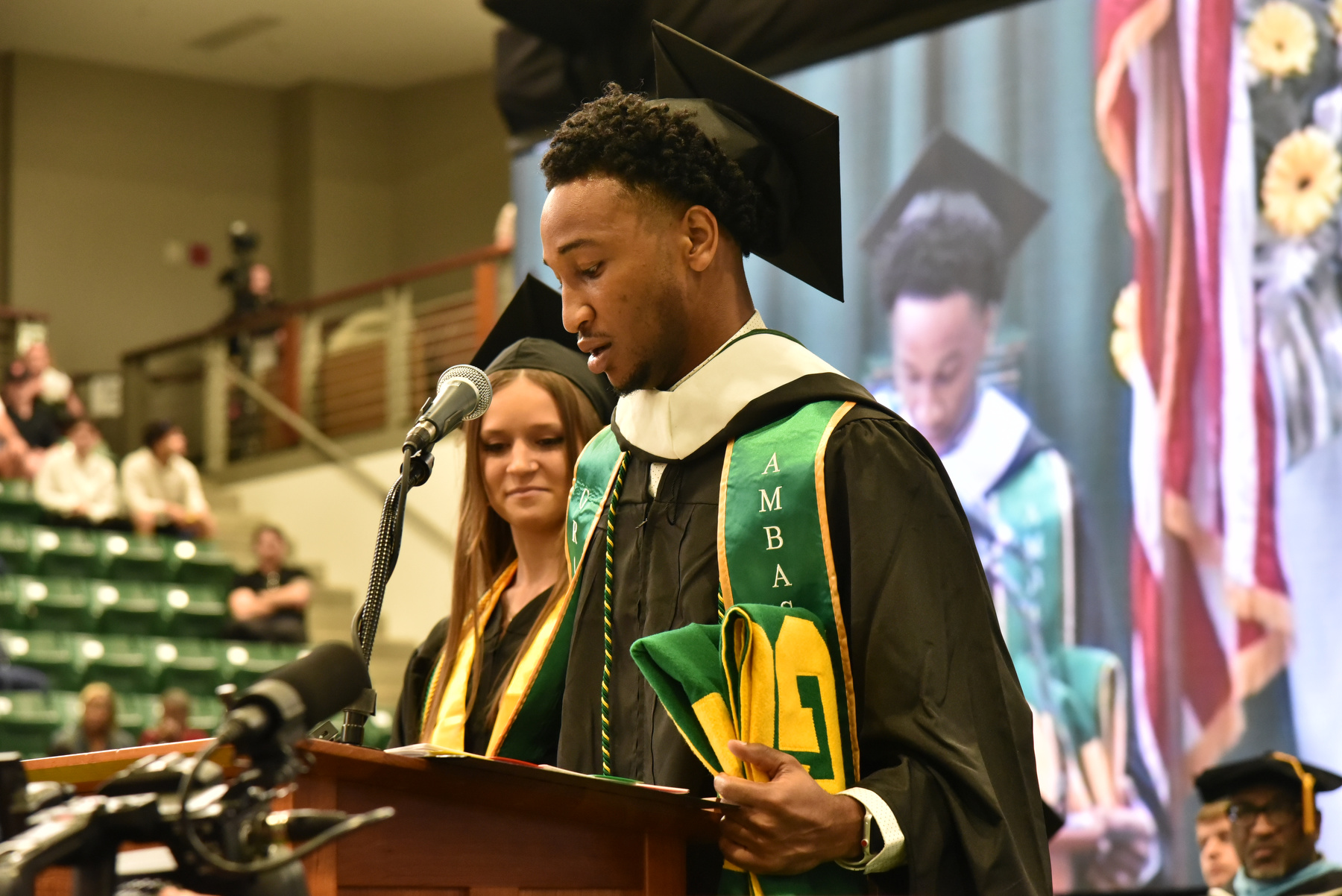 Graduates Audrey Pryll and Asheem Calixte presented the alumni banner at the School of Communication, Media and the Arts and the School of Education commencement ceremony.