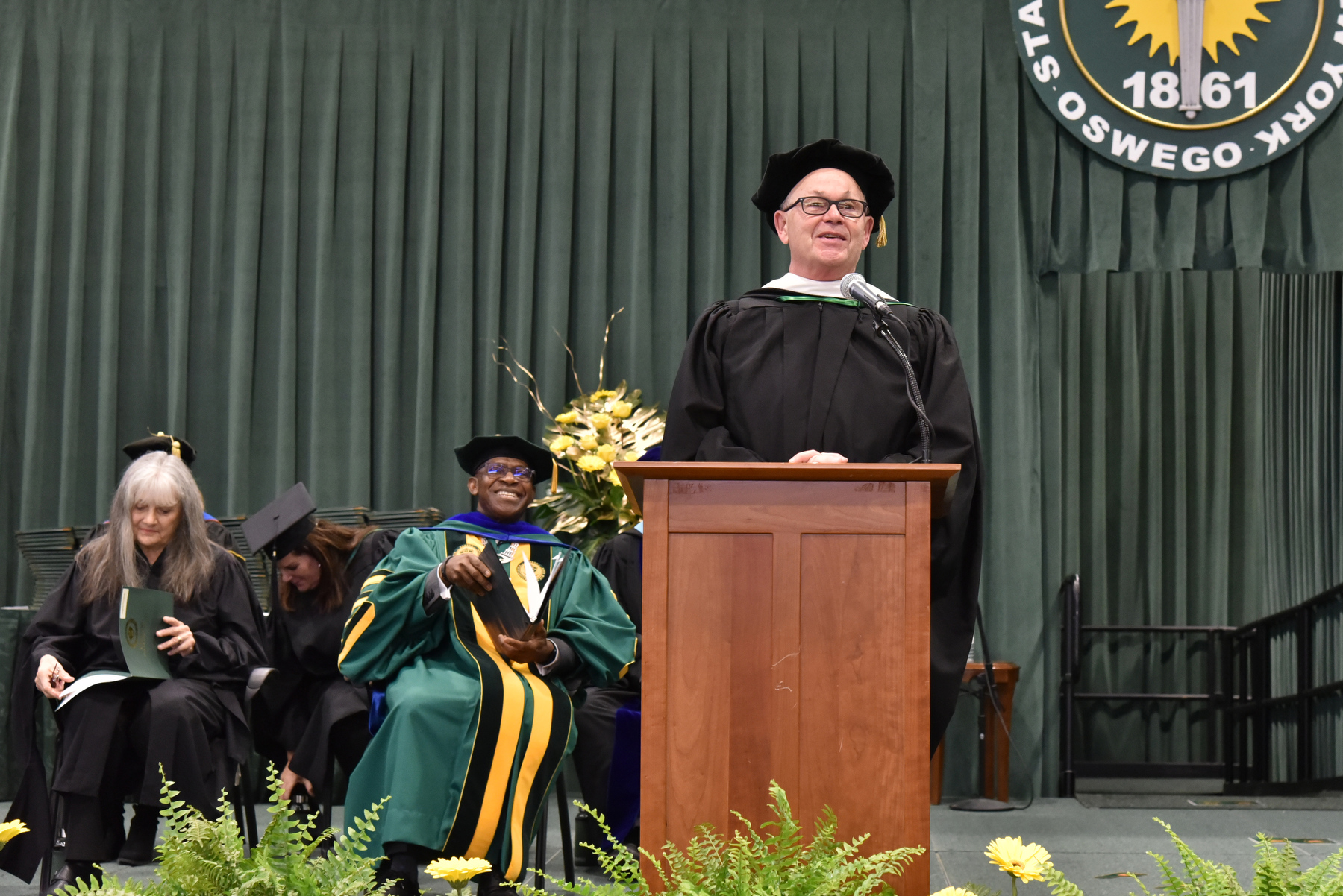 Peter L. Bocko (center), a 1975 graduate and longtime leader with Corning Incorporated, speaks after receiving a State University of New York honorary doctorate degree at Commencement. Through a 41-year career at Corning Incorporated and as an adjunct professor at Cornell University, Bocko is recognized as one of the foremost high-technology glass experts and educators. 