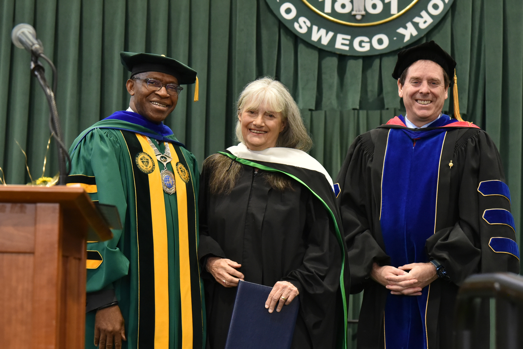 Virginia (Ginny) Donohue, a 1988 Oswego graduate and founder of On Point for College, received a State University of New York honorary doctorate degree at Commencement. Presenting at the commencement ceremony platform is College President Peter Nwosu (left) and Provost and Vice President for Academic Affairs Scott Furlong.
