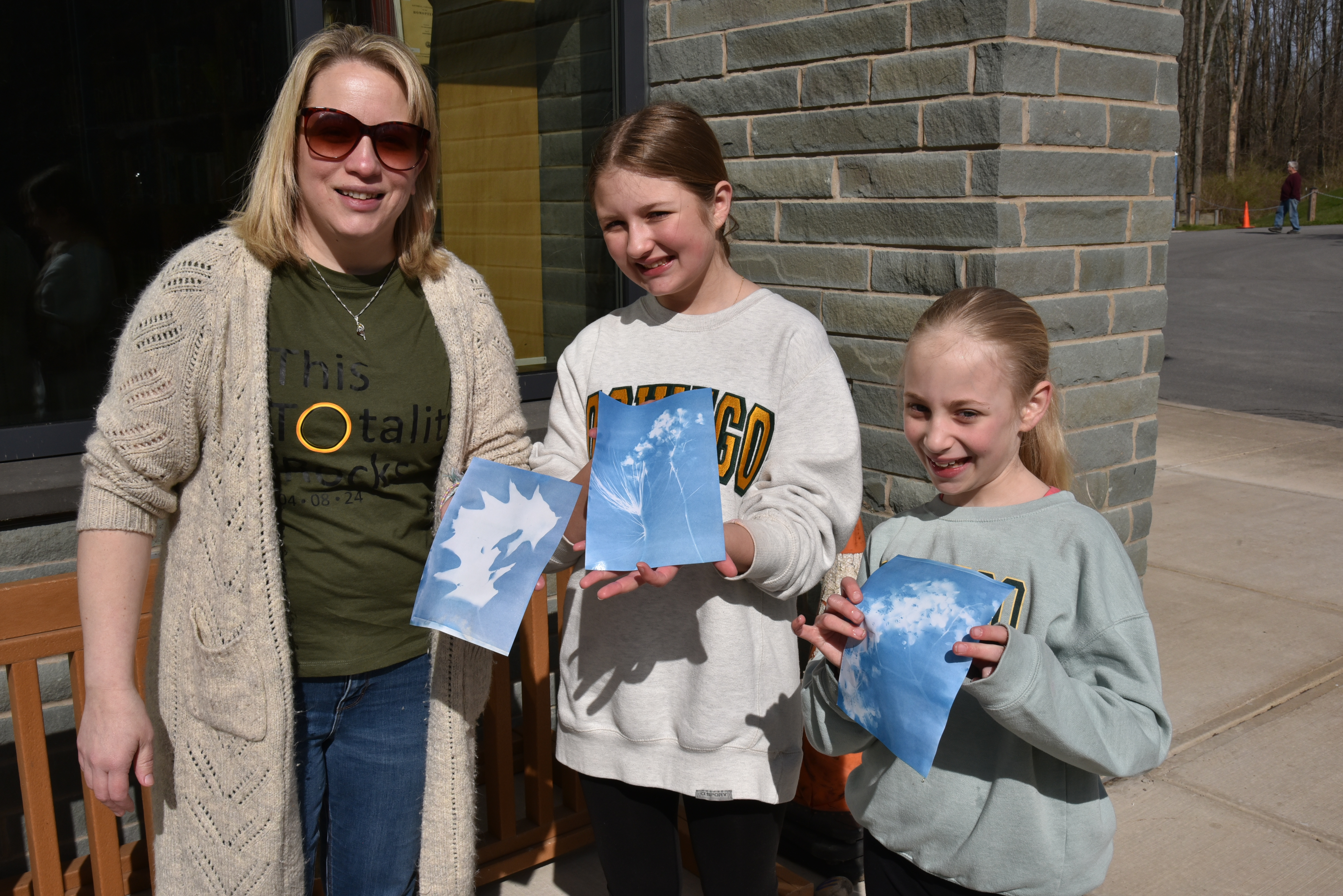 Visitors make artistic cyanotype photograms exposed by the sun during the Rice Creek Field Station Experience during the eclipse day.