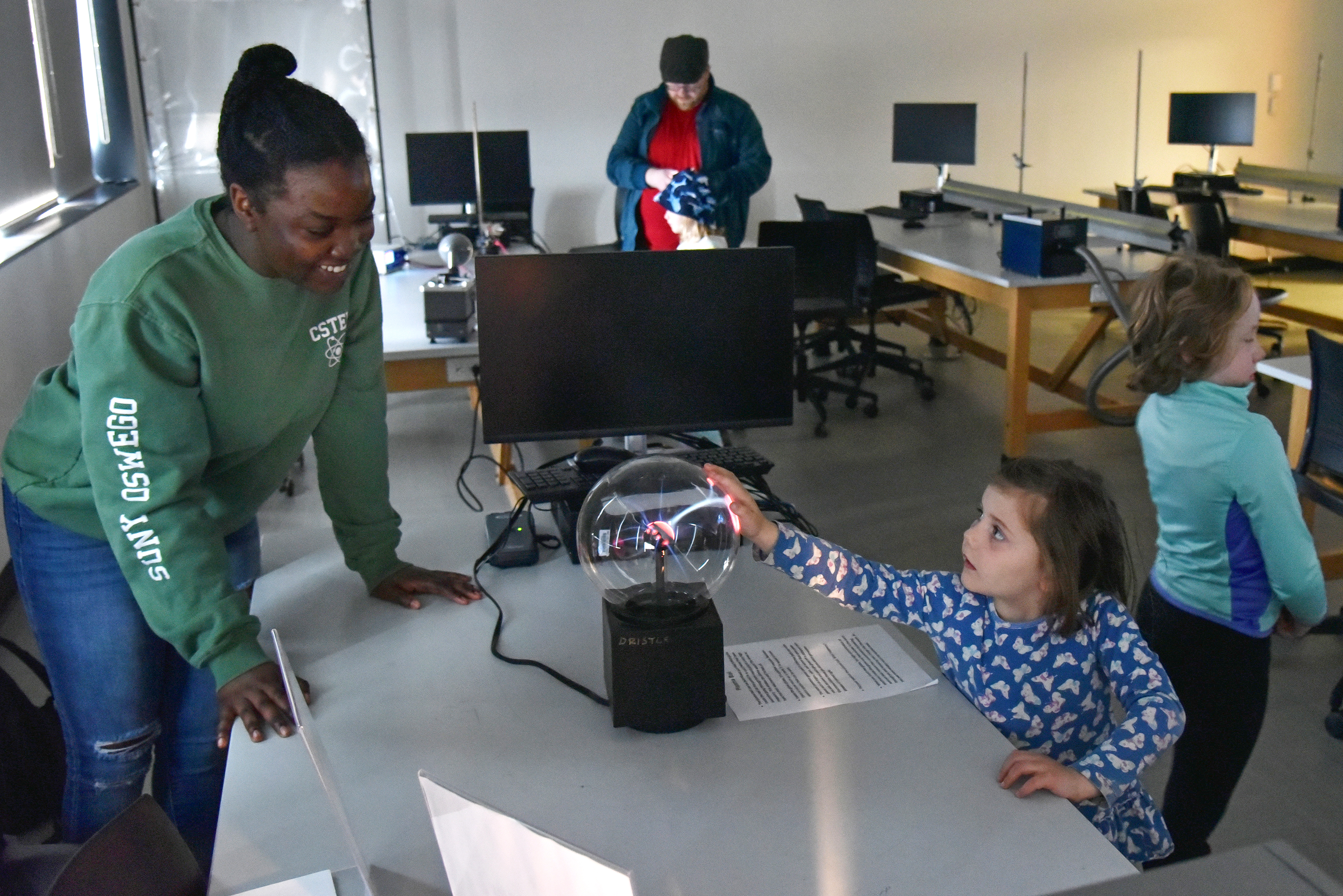 Ahkalia Williams, a senior physics major, helps youngsters experiment with a plasma ball in a Shineman Center physics lab as part of hands-on activities during the day of the eclipse.