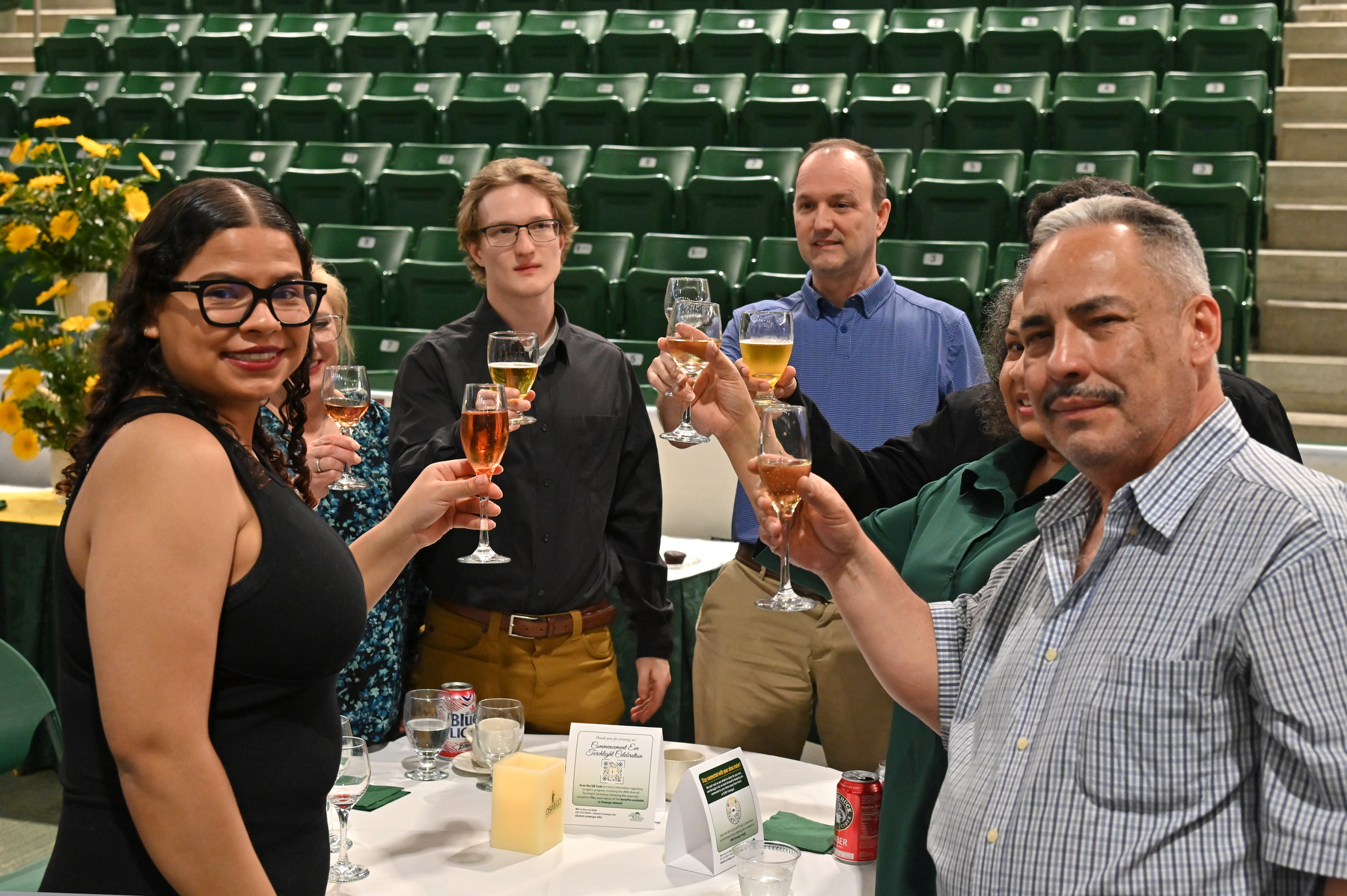 Elaine Rivera (left, foreground), a biological sciences major, and Andrew Bixler (at left in dark shirt), a broadcasting/mass communication major, enjoy the ceremonial Toast to the Graduates with their families during the Commencement Eve Celebratory Reception in the Deborah F. Stanley Arena and Convocation Hall May 16 before the ceremony.