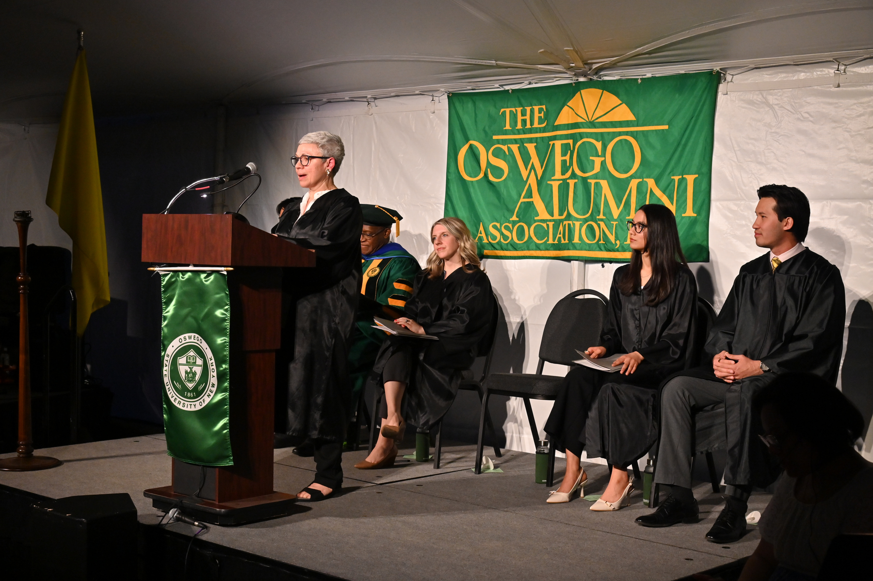Denise J. Grillo ‘84 speaks during the Commencement Eve Torchlight Ceremony on May 16. Also on the platform offering remarks are, pictured, President Peter O. Nwosu; Laura Pavlus Kelly ’09, senior director of alumni engagement and executive director of the alumni association; student speaker Clarissa Karki ’25; and student emcee Eason Lee ’23 M’25.