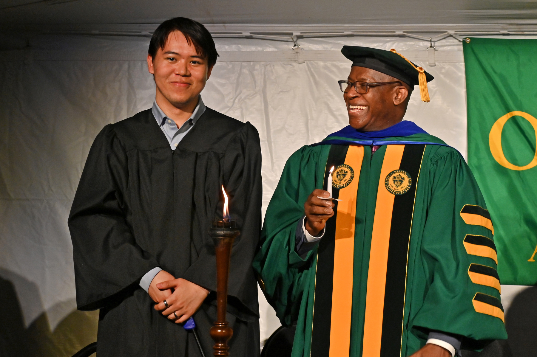 Torchbearer Shaun Lin ’25 and President Peter O. Nwosu light the torch at the platform before passing the ceremonial flame to the candles held by graduating seniors, their families, friends and other audience members during the Commencement Eve Torchlight Ceremony on May 16.
