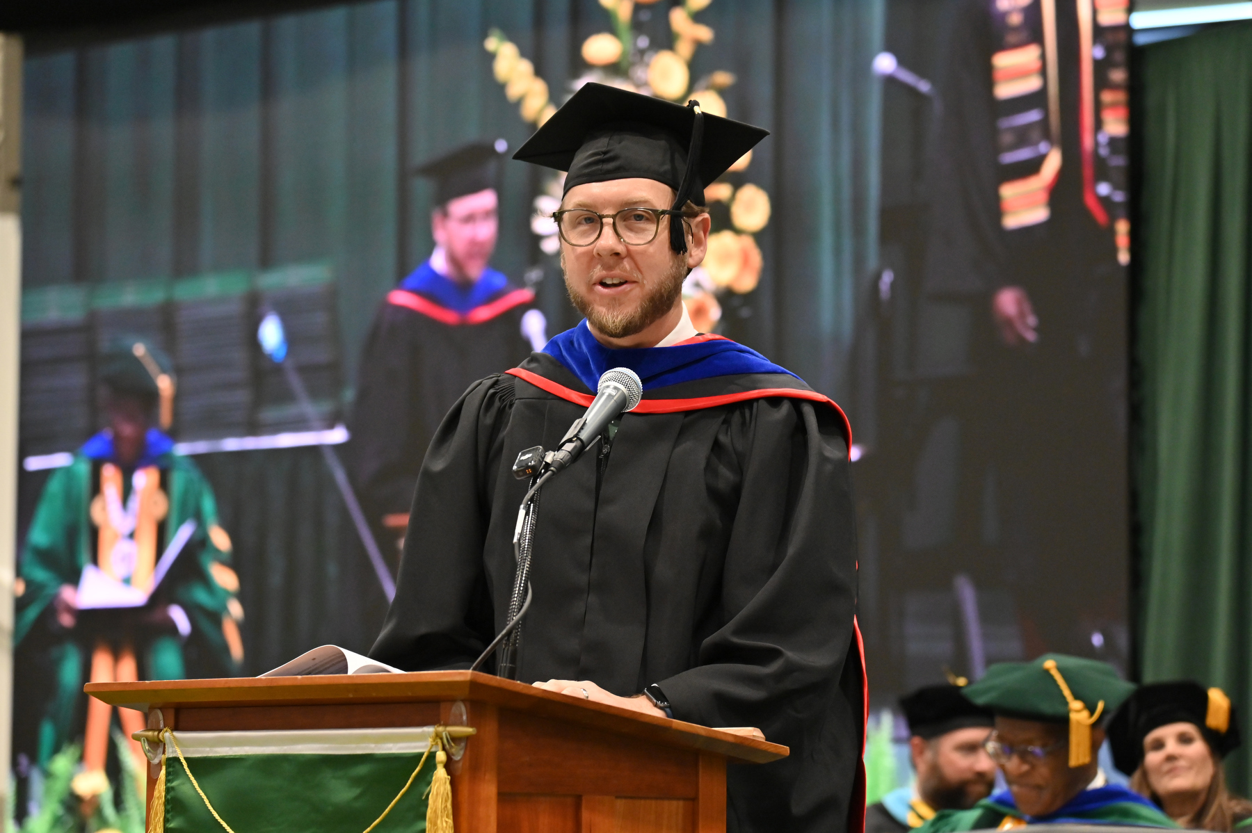 Heath Wood, vice president for university advancement, introduces the student presenters of the Class of 2025 Alumni Banner for each of the three ceremonies, here for the School of Business ceremony.
