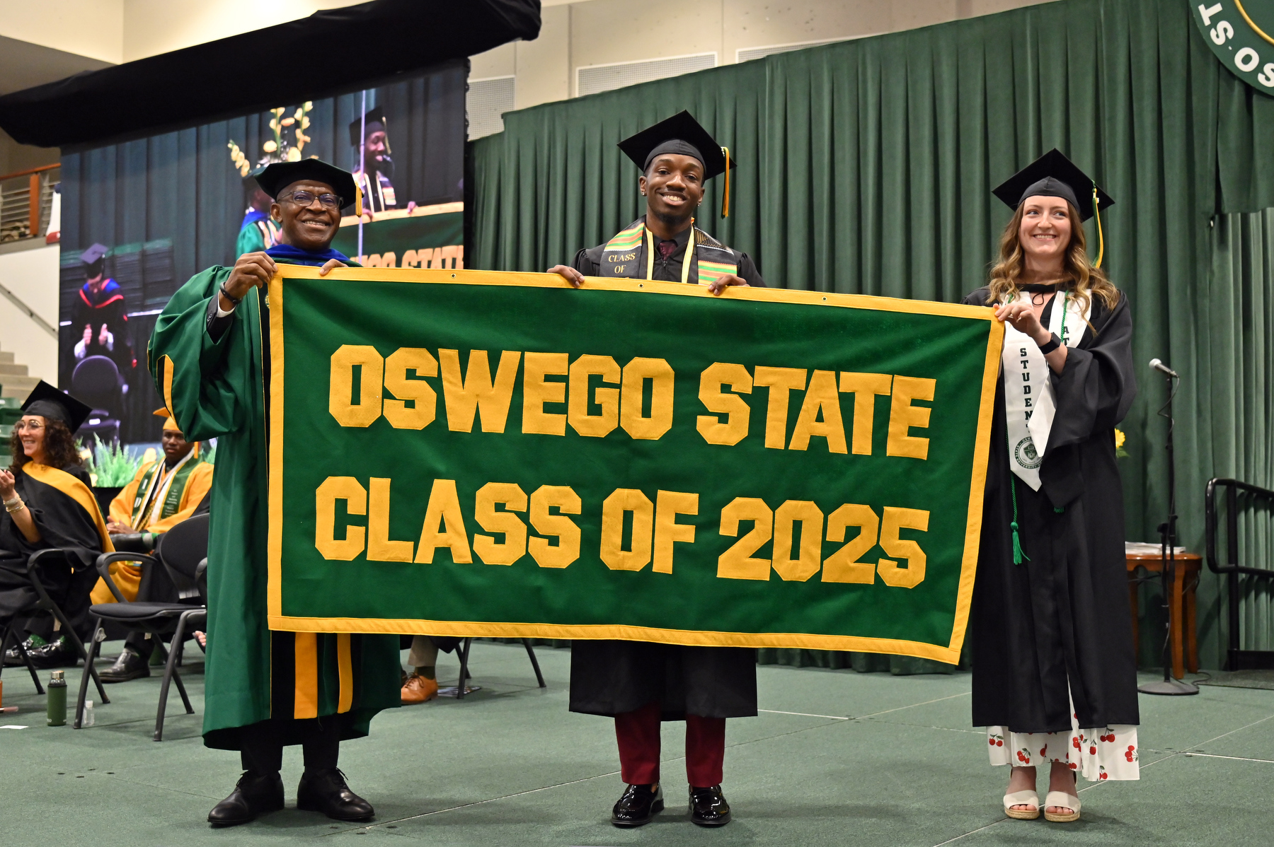 Jaylen Cameron and Rachel Corbett present the Class of 2025 Alumni Banner to President Peter O. Nwosu at the School of Business ceremony.