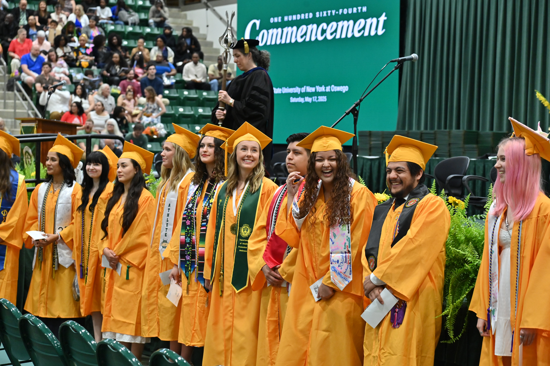 Summa cum laude honors graduates line the front of the platform as graduates enter the hall for the beginning of the ceremony for the 4 p.m. School of Communication, Media and the Arts and the School of Education.