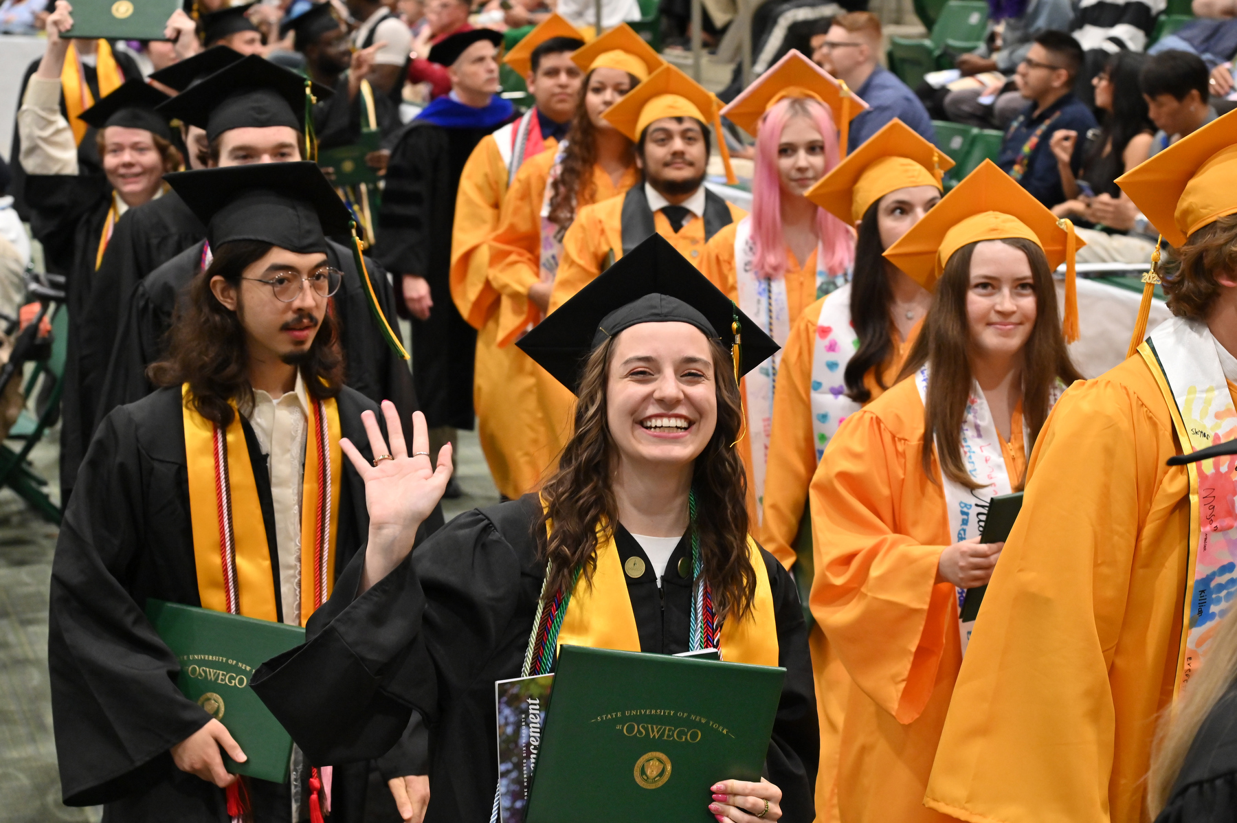 Melinda Brancato waves as she and fellow graduates exit the Deborah F. Stanley Arena and Convocation Hall after the School of Communication, Media and the Arts and the School of Education ceremony.