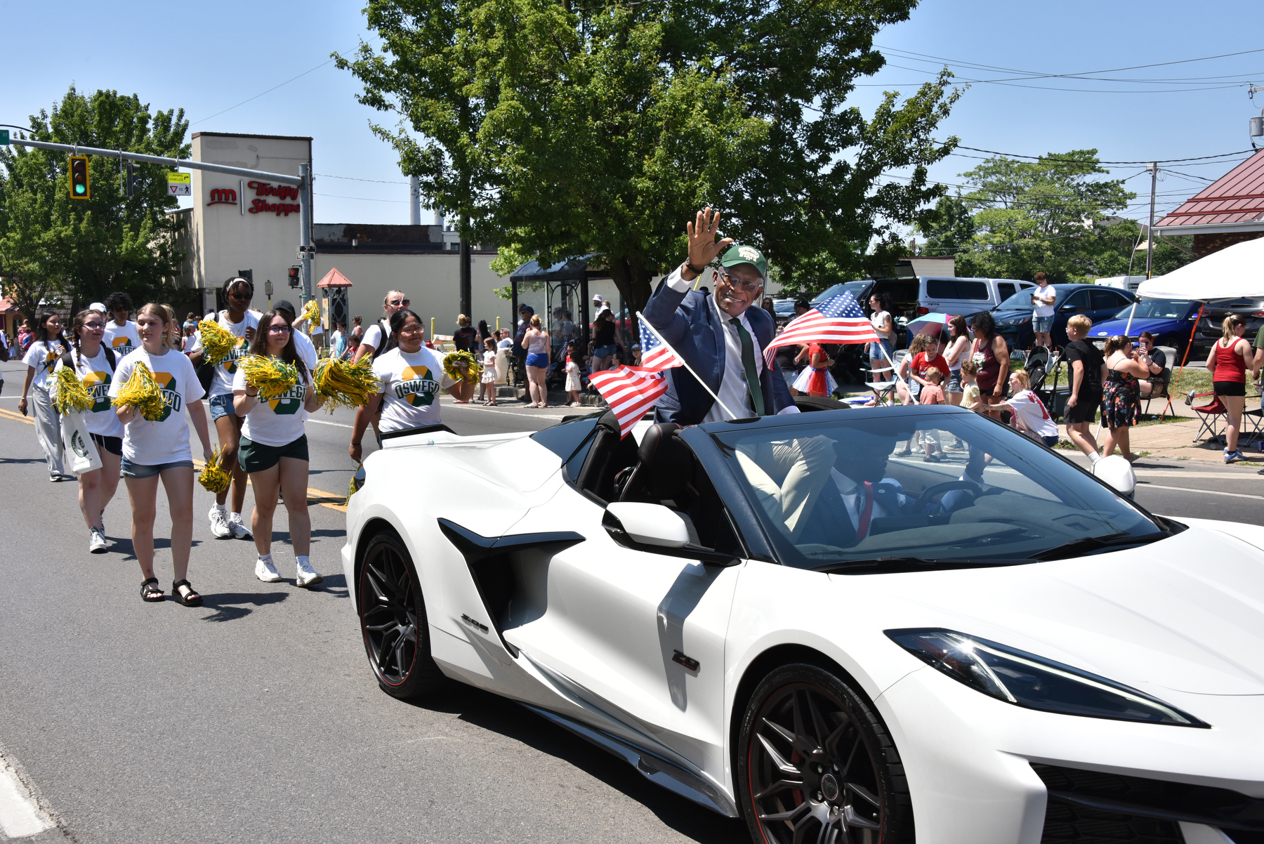 President Peter O. Nwosu waves to enthusiastic spectators lining Bridge Street while leading the procession as grand marshal of the 2025 City of Oswego Independence Day Parade. Laker students and staff joined him in the annual celebration, this year held July 6 from Oswego High School to Fort Ontario. Burritt Motors provided the vehicle for President Nwosu to lead the parade.