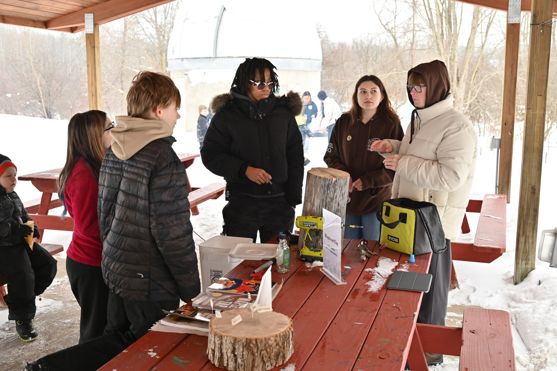 Rice Creek Field Station's annual Celebrate Snow Winter Festival included information on tapping sugar maple trees to collect sap used to make maple syrup. Office of Sustainability Interns demonstrating the process are, from left, sophomore zoology majors Jade Emmanuel and Emily DeLuca, and Logan Tillinghast, a sophomore environment Earth science major. 