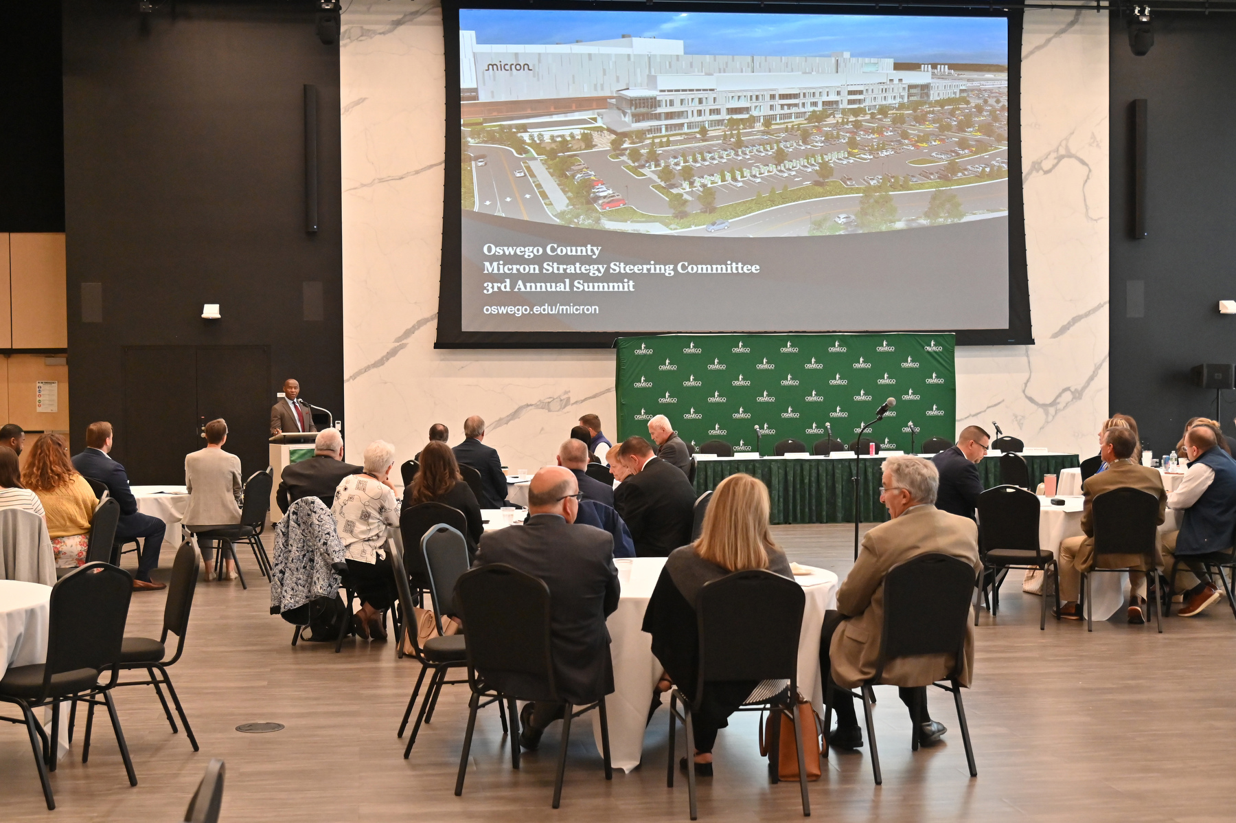 President Peter O. Nwosu welcomes panelists and guests to a summit meeting of the Oswego County Micron Strategy Steering Committee who assembled to present updates on Oswego County’s preparations for Micron Technology’s ongoing transformative investment in Central New York. 