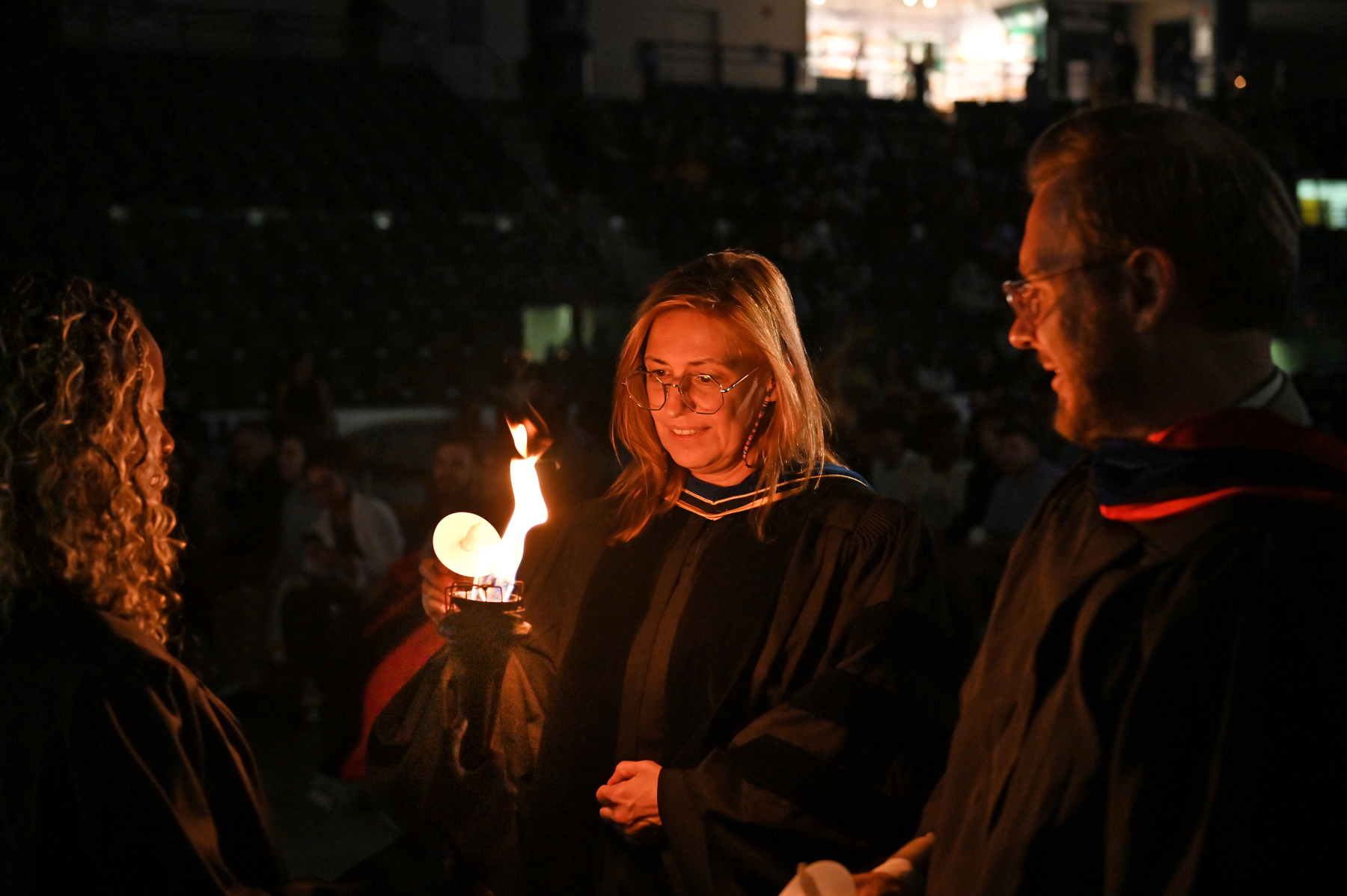Student Association President and Torchbearer Precious James lights the candles for Kate Pechenkina, SUNY Oswego's new provost and vice president for academic affairs, and Heath Wood, vice president for university advancement, during the 37th annual Welcoming Torchlight Ceremony on Aug. 20.
