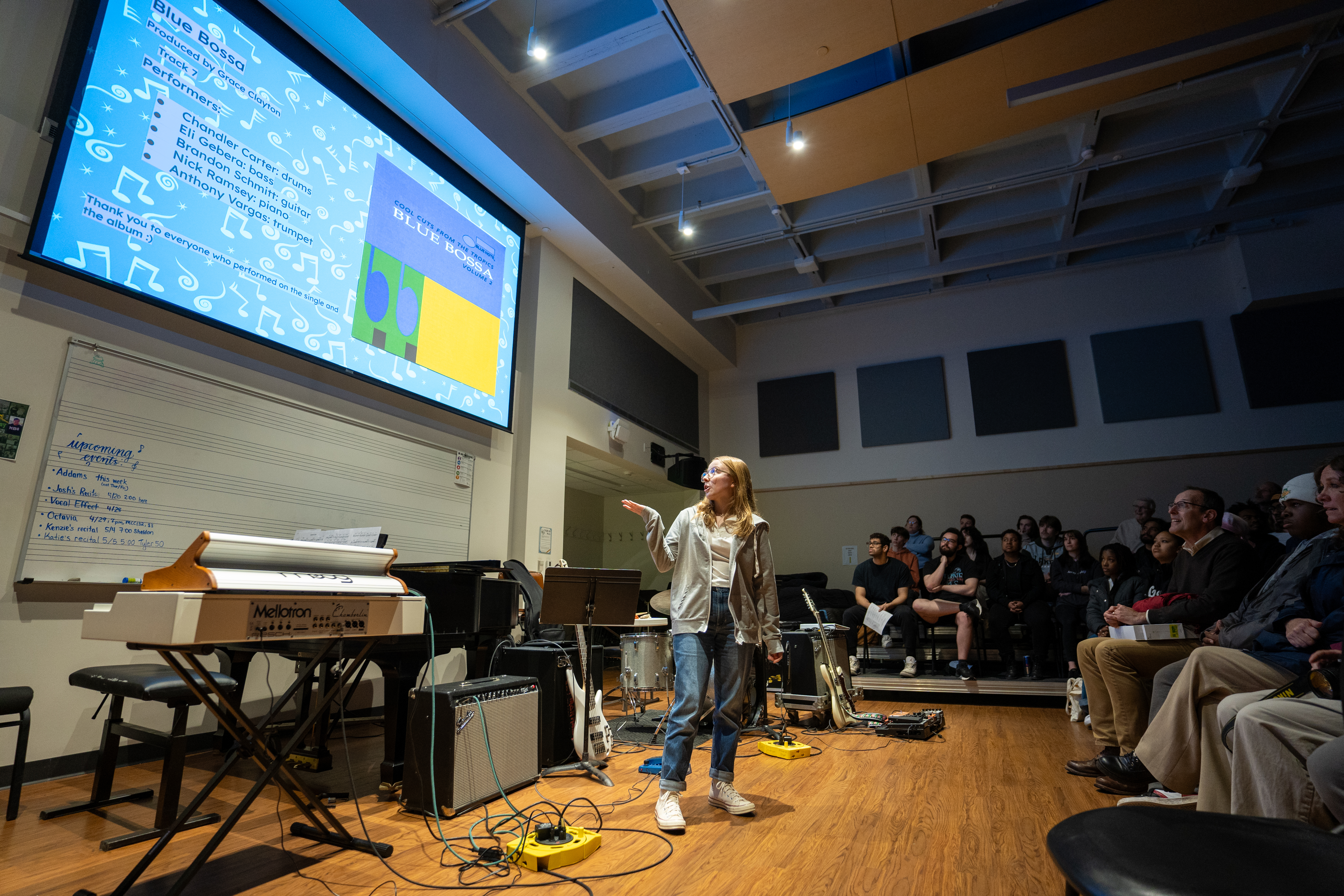 Audio recording and production major Grace Clayton explains and introduces a rendition of “Blue Bossa,” featuring student musicians during the Audio Recording and Production Recital at Quest. Clayton and other students in “Recording IV,” a senior seminar course for audio recording and production majors, showcased work from their semester-long album production projects, playing singles from the albums. 