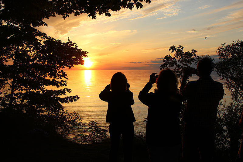 Alumni take photos of sunset over Lake Ontario