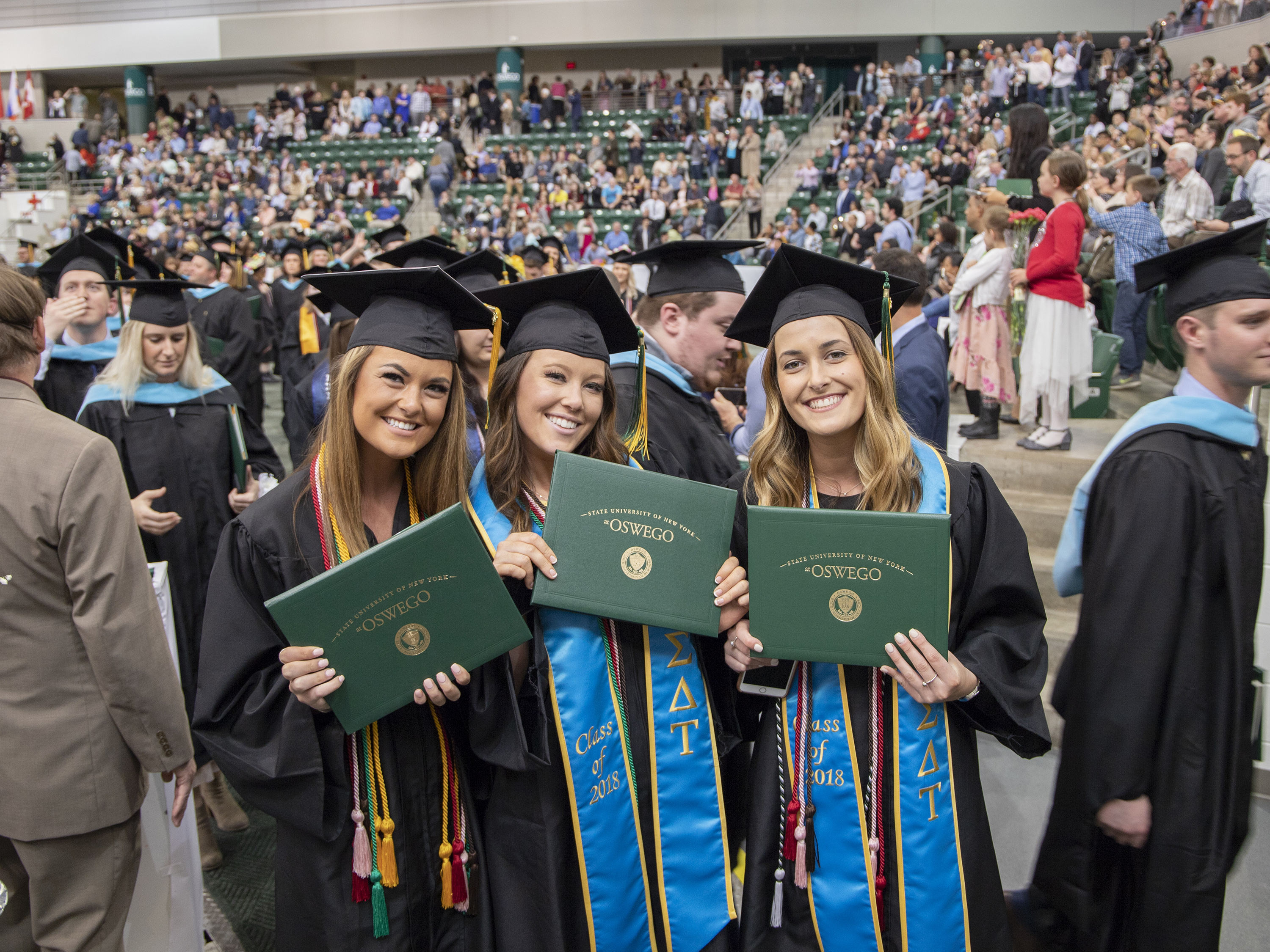 Graduates smile and hold diploma covers