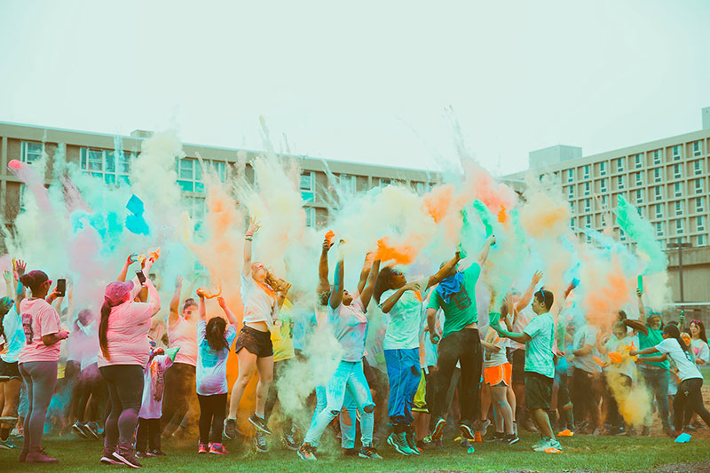 Students throwing colorful powder on runners