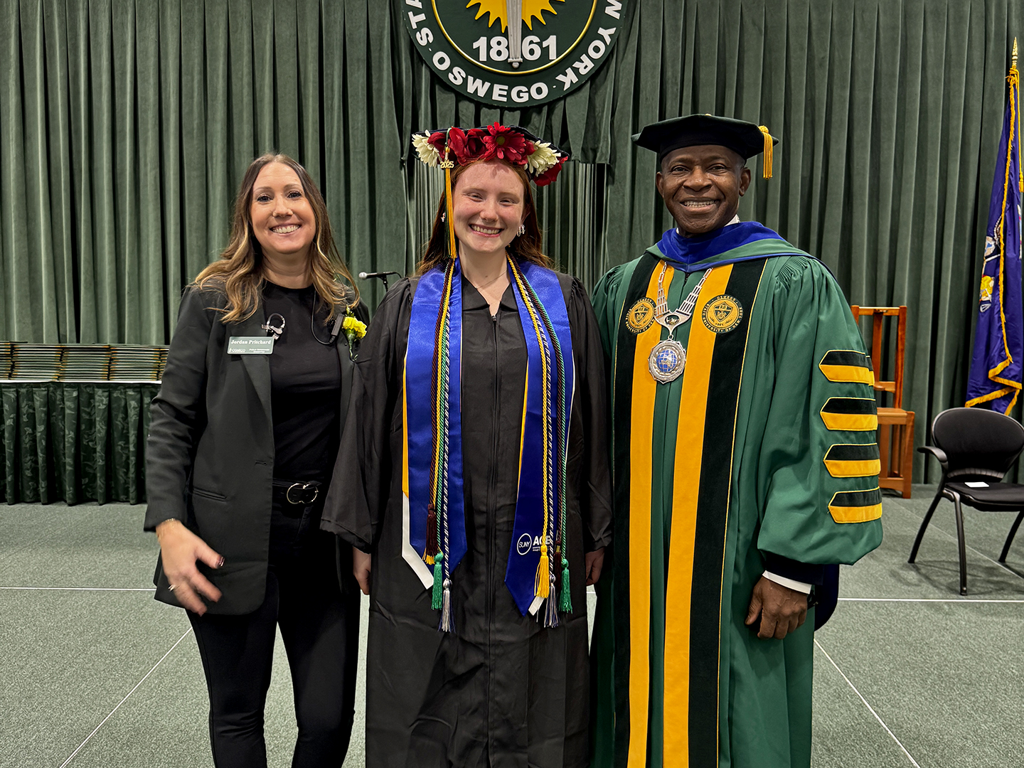 Emily Colledge, the first student to graduate from SUNY Oswego's ACE program, receives congratulations from Jordan Pritchard, director of Oswego's ACE program, and President Peter O. Nwosu