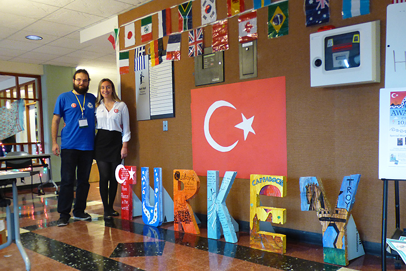 Turkish students Emir Tortopoglu and Fem Koymen stand in Hart Hall lobby next to artwork connecting to their home country