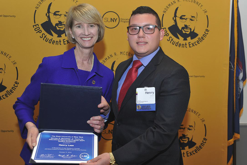 Senior double major in business administration and finance Hennry Leon is congratulated by SUNY Chancellor Kristina B. Johnson