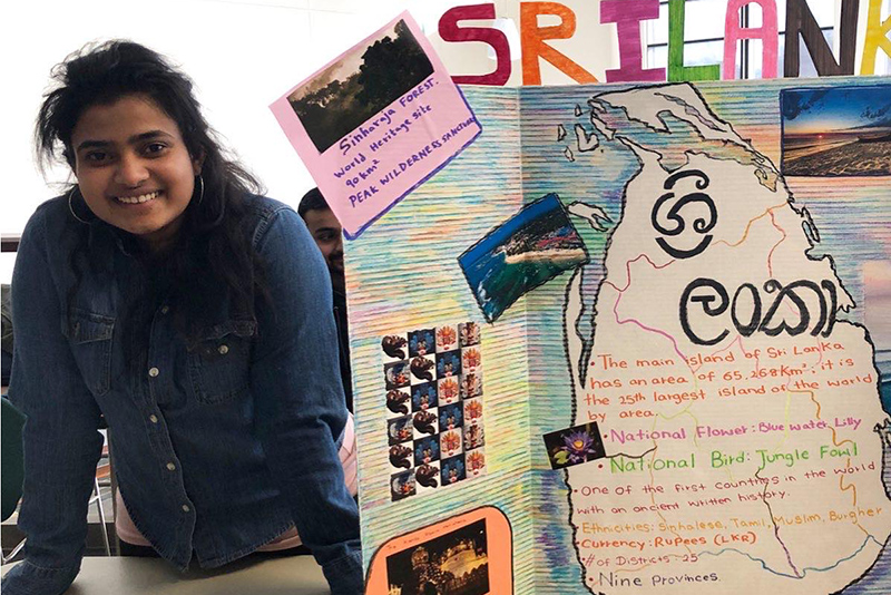 Sri Lankan student Oshadhi Theshan Palanda Liyanage Perera poses next to the board she decorated with information about her home country