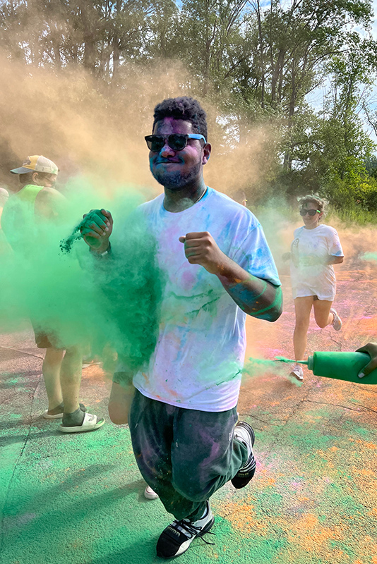 Student runs through green chalk at the annual Color Run on SUNY Oswego's campus.