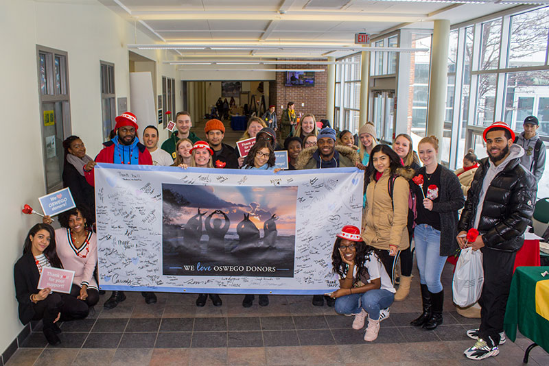 Enthusiastic students pose around Love-A-Donor Day banner