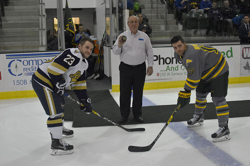 Vietnam War veteran and Purple Heart recipient Glynn English readies to drop a ceremonial puck with captains of Oswego and Canton men's hockey teams