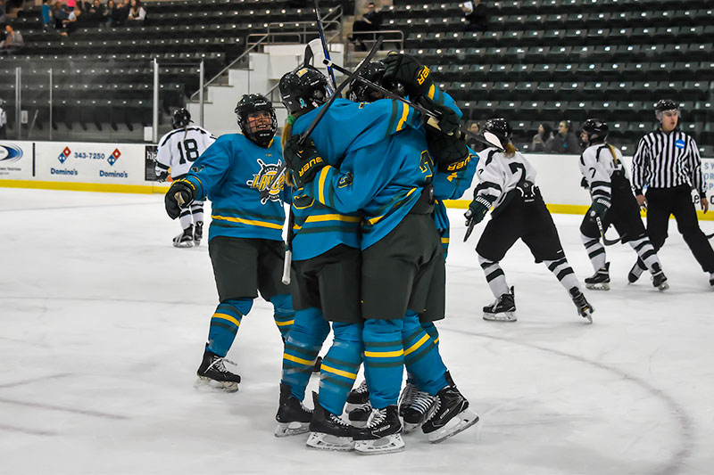 Laker women's hockey players celebrate goal in a big hug