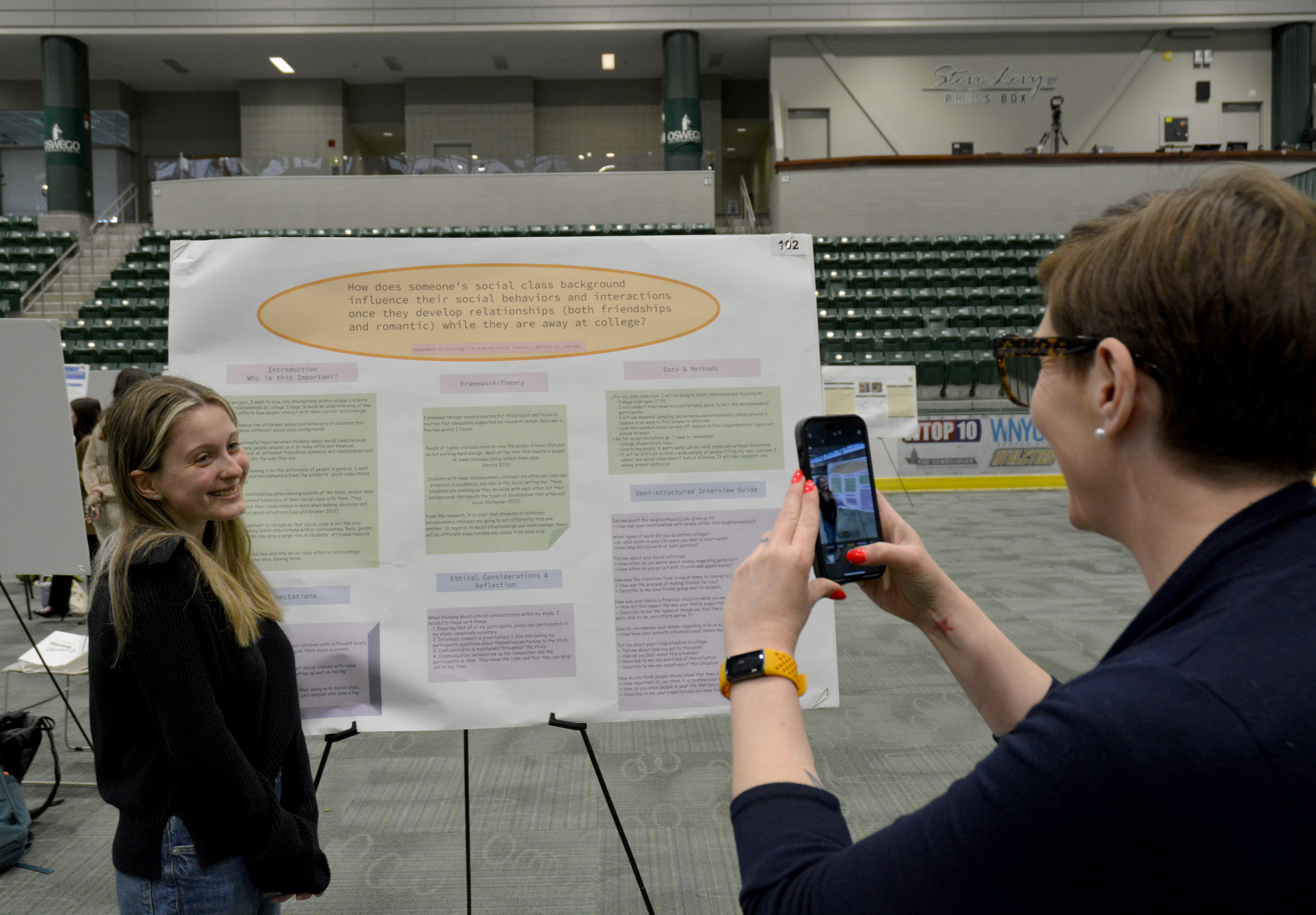 Sociology major Olivia Troendle poses for a photo by sociology faculty member and research mentor Emily Estrada on a poster they collaborated on, titled “How Does Someone’s Social Class Background Influence Their Social Behaviors and Interactions Once They Develop Relationships (Both Friendships and Romantic) While They Are Away at College?” during the April 17 Quest poster session.