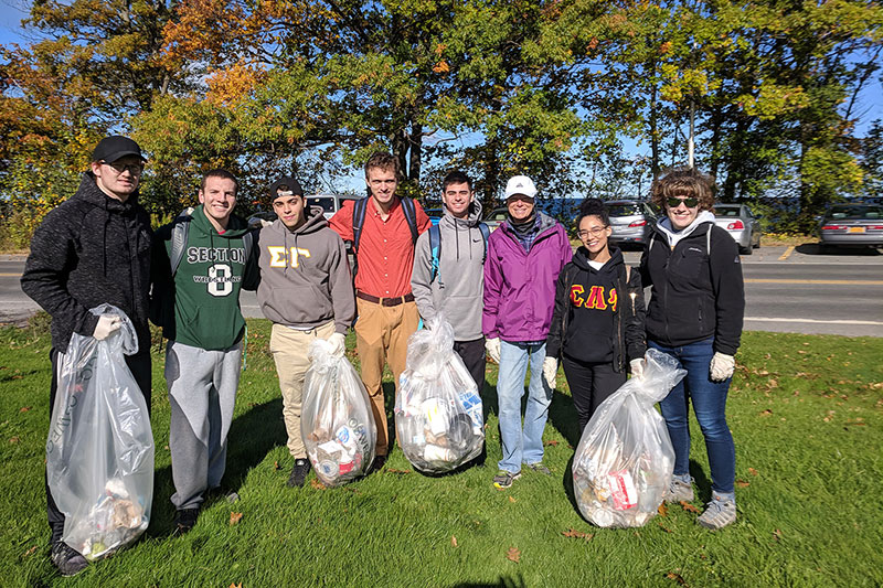 Students showing bags of waste they picked up during a lakeshore cleanup