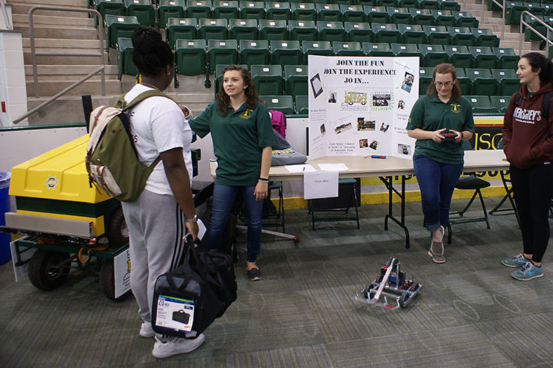 Team Mini members with mini-Zamboni and robot speak to students