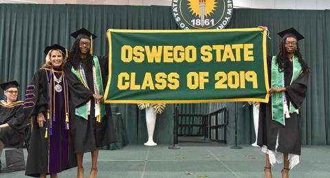 Campbell twins with President Deborah F. Stanley and Class of 2019 banner