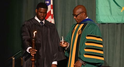 SUNY Oswego President Peter O. Nwosu lights his candle after Torchbearer and Student Association President Aiden Wilson lights the traditional torch on the platform during Welcoming Torchlight Ceremony on Aug. 21.