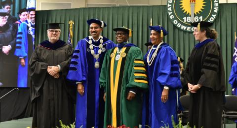 Members of the platform party presented SUNY Oswego’s 11th President Peter O. Nwosu (center) with the ceremonial hood and medallion during the Sept. 27 inauguration in the Deborah F. Stanley Arena and Convocation Hall.