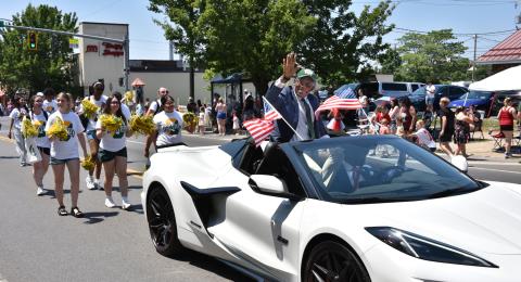 President Peter O. Nwosu waves to enthusiastic spectators lining Bridge Street while leading the procession as grand marshal of the 2025 City of Oswego Independence Day Parade. Laker students and staff joined him in the annual celebration.
