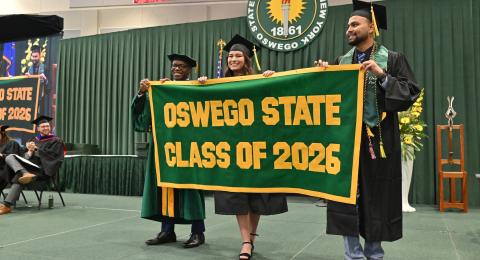 Brooke Holzlein and Meet Patel present the Class of 2026 Alumni Banner to President Peter O. Nwosu on the commencement platform during the 12:30 p.m. ceremony for the College of Business and Entrepreneurship. 