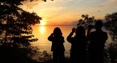 Alumni take photos of sunset over Lake Ontario