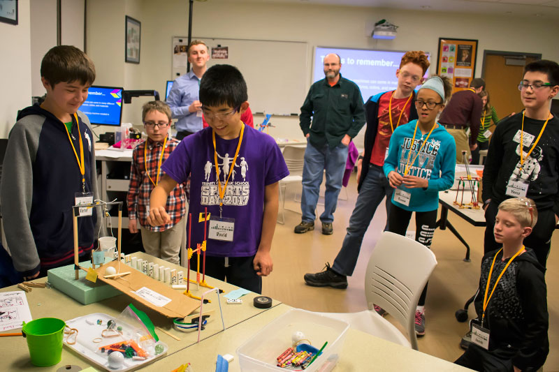 Elementary students work on working on Rube Goldberg devices