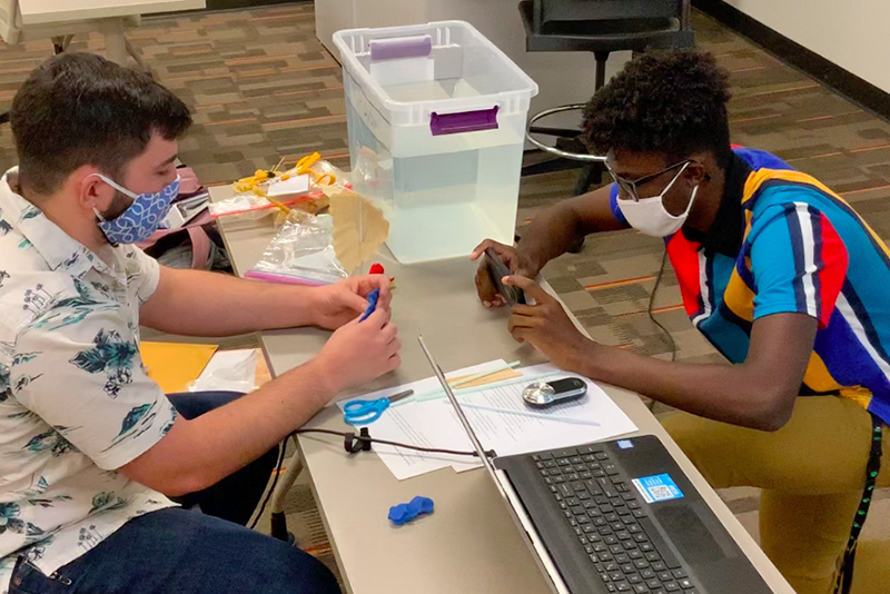 Technology education students Chris Corr (left) and Carrington Vaughn teach a live video conference lesson on water transportation to their students from Young Inventors program