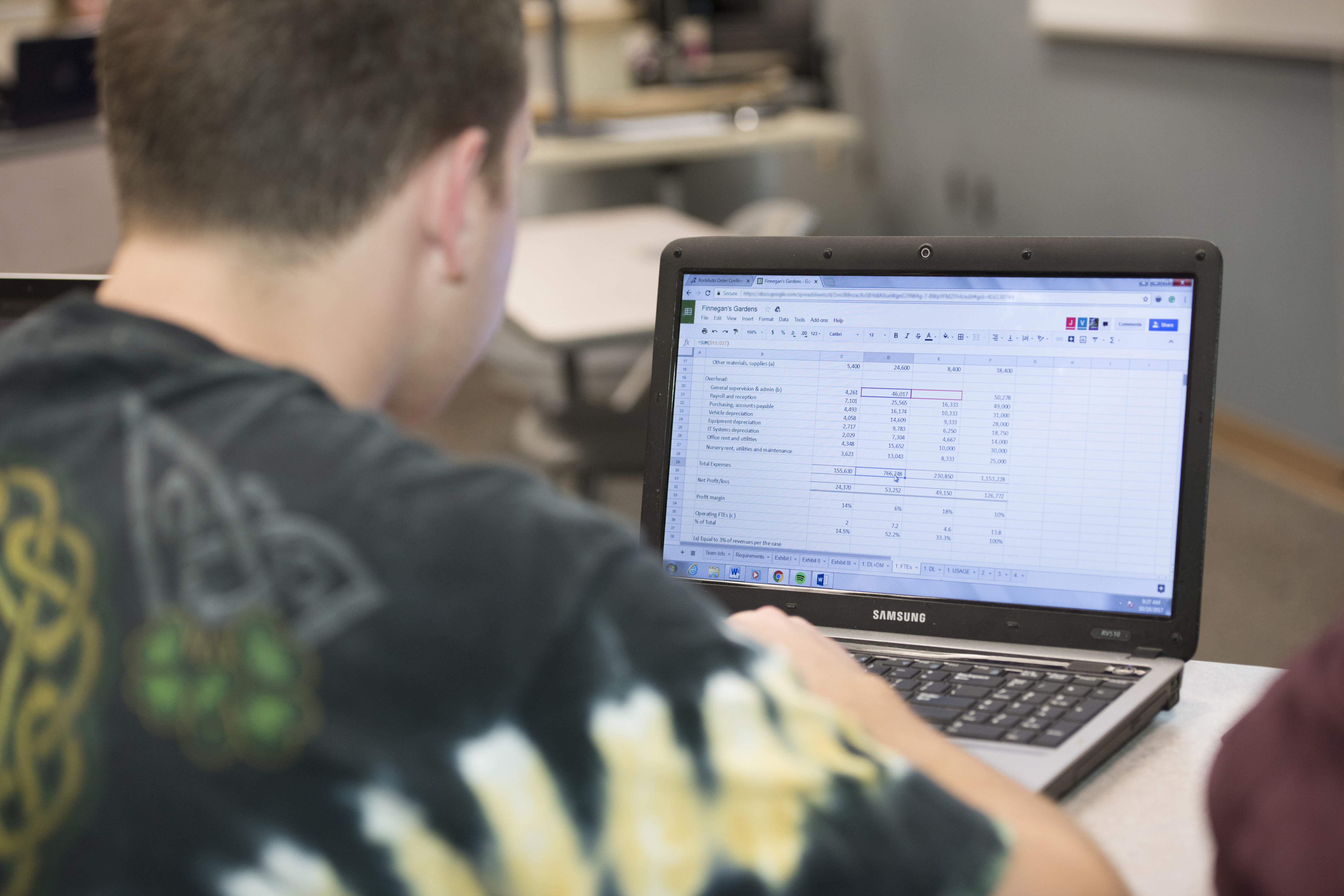 male student typing on a laptop with an excel file open